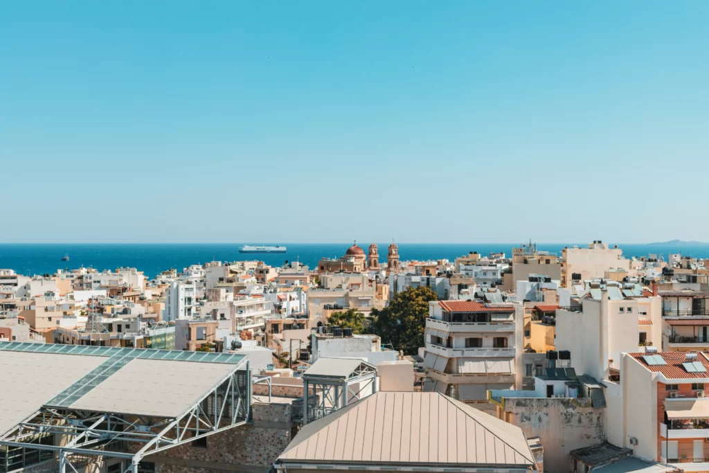Panoramablick über die Küstenstadt auf Zypern mit mediterranen Gebäuden, Kirchtürmen und Blick auf das Mittelmeer unter klarem Himmel.